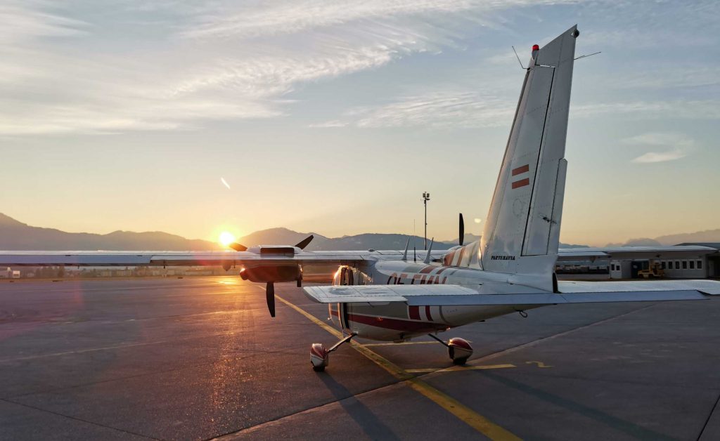 Flugzeug auf einem Flugfeld, im Hintergrund eine untergehende Sonne